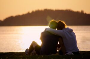 Two people hugging each other watching a sunset across the water. Without Doing Anything