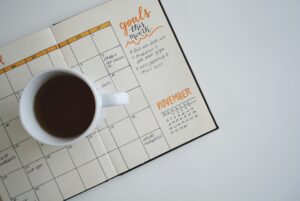 Planner with calendar and goals written down, and a coffee mug on top. Have a fresh start.