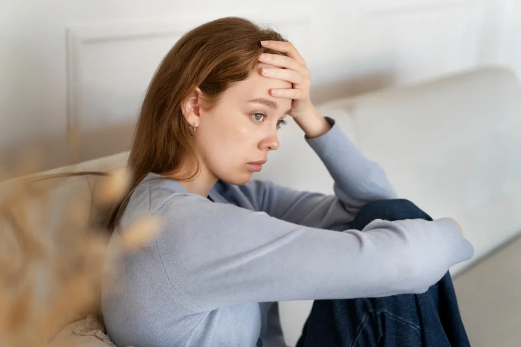 a women is holding her forehead and looking away