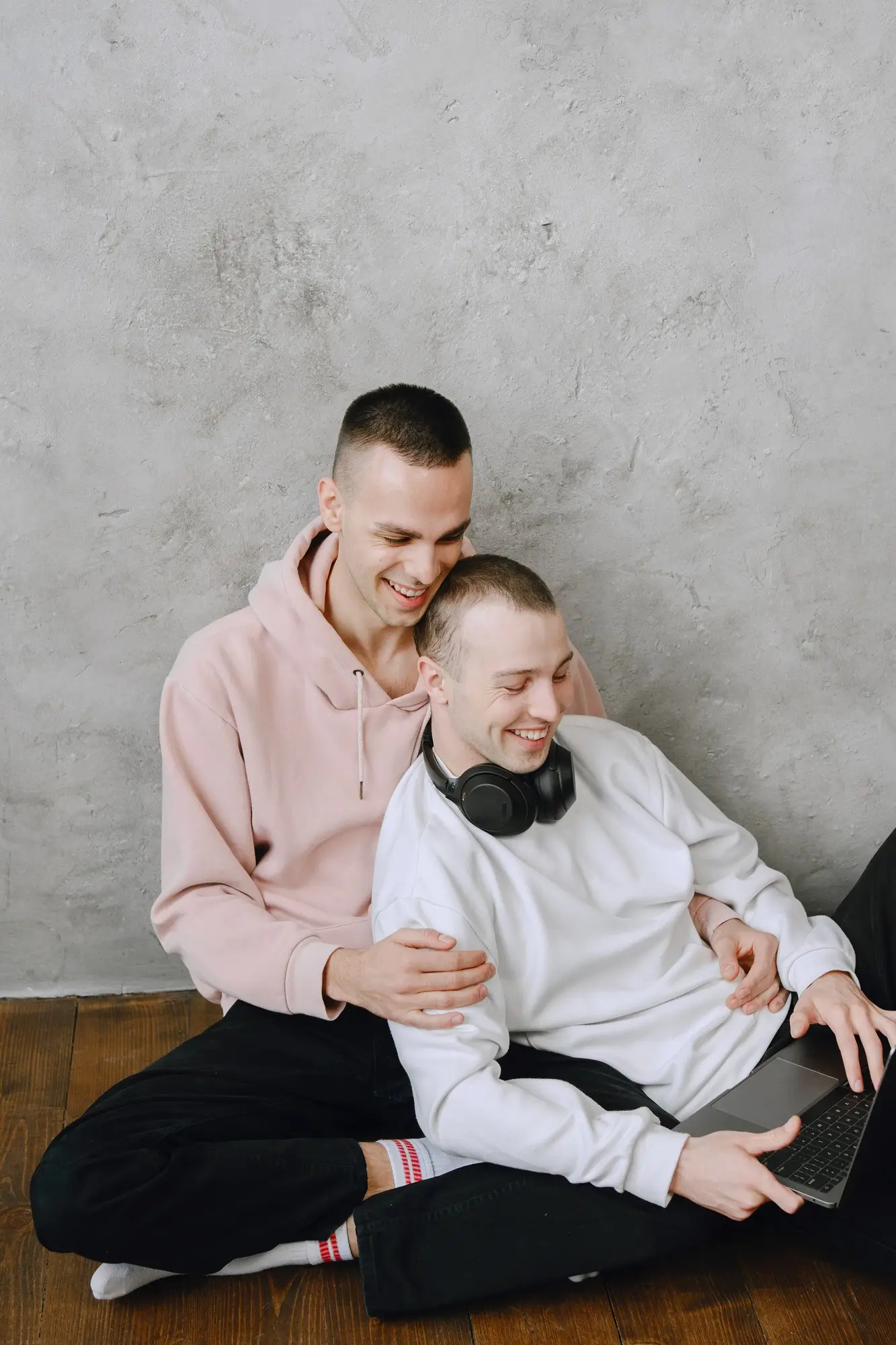 Young gay couple sitting on floor using laptop